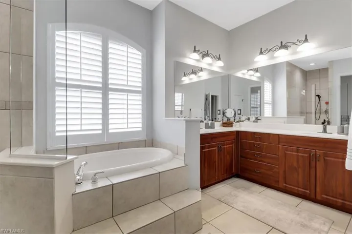 Full bath with a bath, double vanity, healthy amount of natural light, and tile patterned flooring