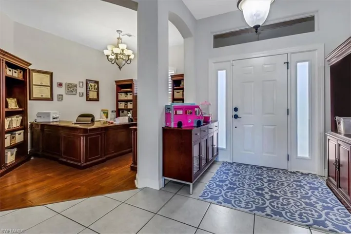 Entrance foyer with tile patterned floors, a chandelier, and arched walkways