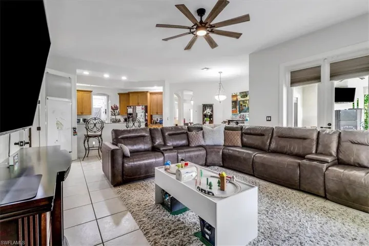 Living room featuring a ceiling fan, light tile patterned flooring, and recessed lighting