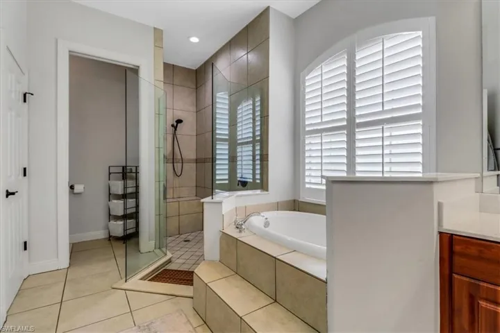 Full bath featuring tiled shower, a garden tub, vanity, tile patterned floors, and recessed lighting