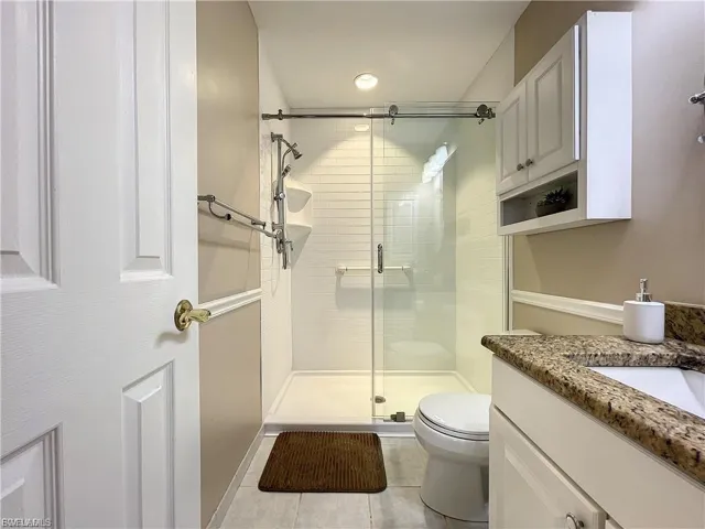 Full bath featuring vanity, a stall shower, light tile patterned floors, and recessed lighting