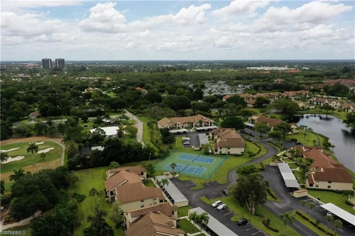 Aerial view of residential area featuring a golf club and a nearby body of water