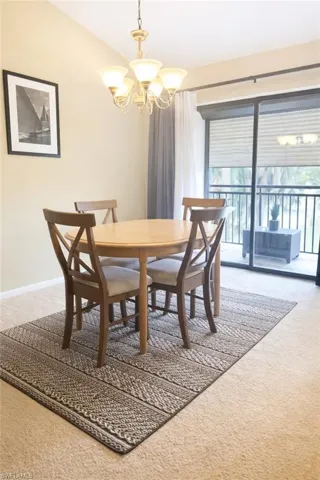 Carpeted dining space featuring a chandelier and vaulted ceiling