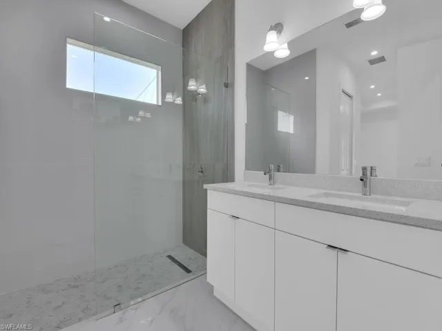 Primary Bathroom featuring double vanity and tiled shower