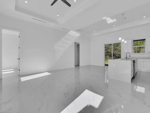 Empty room with ceiling fan, a raised ceiling, ornamental molding, and sink
