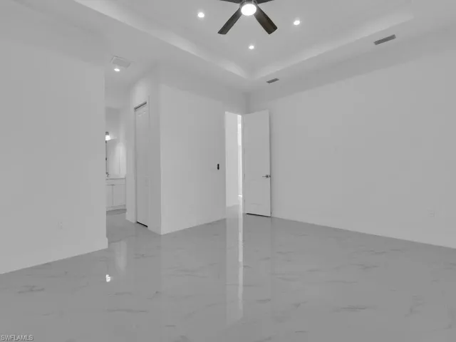 Primary bedroom with ceiling fan and a tray ceiling