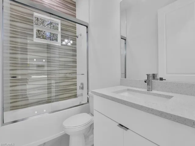 Full bathroom featuring vanity, toilet, and enclosed tub / shower combo.
