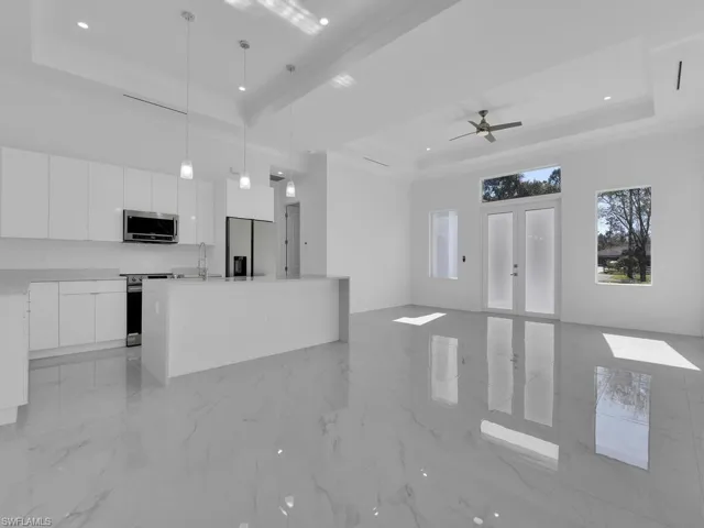 Kitchen with pendant lighting, a raised ceiling, white cabinetry, and stainless steel appliances