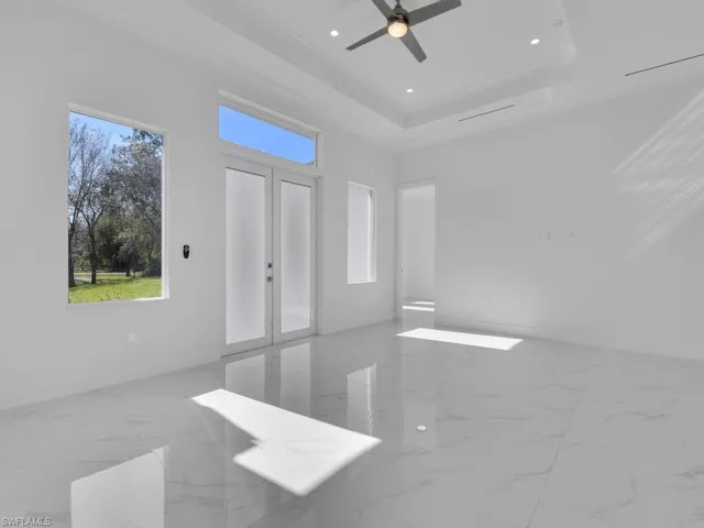 Empty room with a raised ceiling, ceiling fan, and crown molding