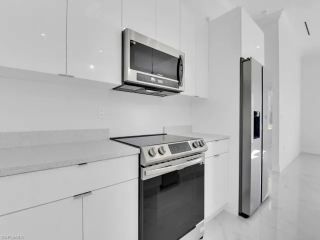 Kitchen featuring stainless steel appliances and white custom wood cabinetry
