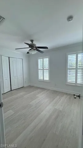 Unfurnished bedroom featuring light wood-style floors, ornamental molding, a closet, and a ceiling fan