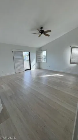 Unfurnished living room with light wood-style flooring, healthy amount of natural light, a ceiling fan, and lofted ceiling