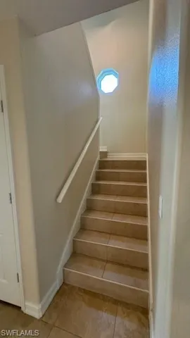 Staircase with tile patterned flooring and baseboards