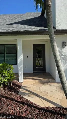 Entrance to property featuring a shingled roof and stucco siding