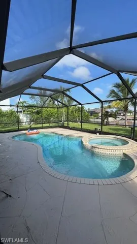 View of pool featuring a sunroom, a pool with connected hot tub, a patio area, and a lanai
