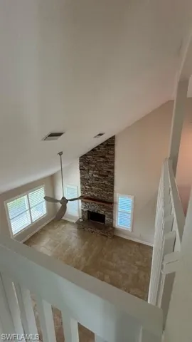 Staircase featuring a stone fireplace and high vaulted ceiling