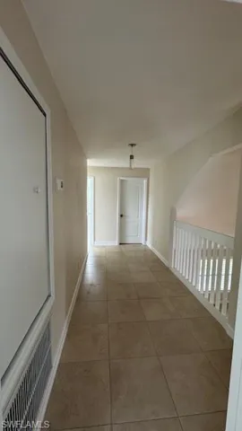 Corridor with light tile patterned flooring and baseboards