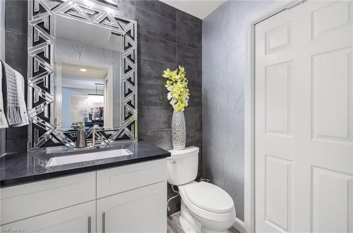 Bathroom with tile walls, large vanity, and toilet