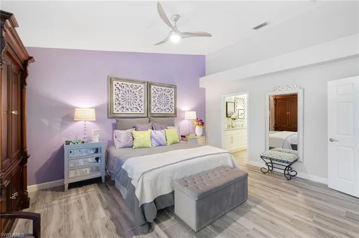 Bedroom featuring ensuite bath, ceiling fan, light hardwood / wood-style floors, and lofted ceiling