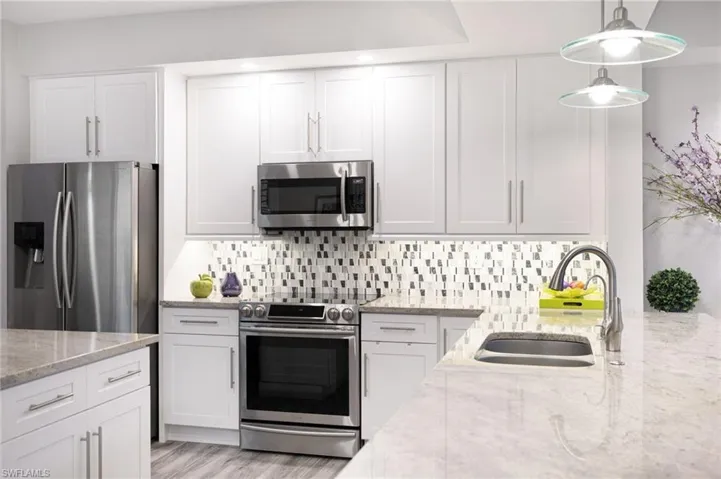 Kitchen featuring white cabinets, appliances with stainless steel finishes, sink, and light wood-type flooring