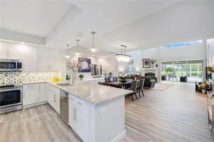 Kitchen featuring light stone countertops, appliances with stainless steel finishes, kitchen peninsula, backsplash, and sink