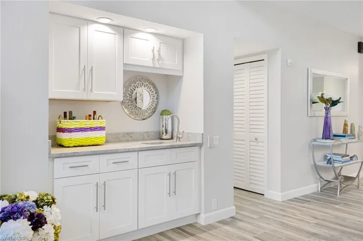Kitchen with white cabinetry, sink, light hardwood / wood-style floors, and light stone counters