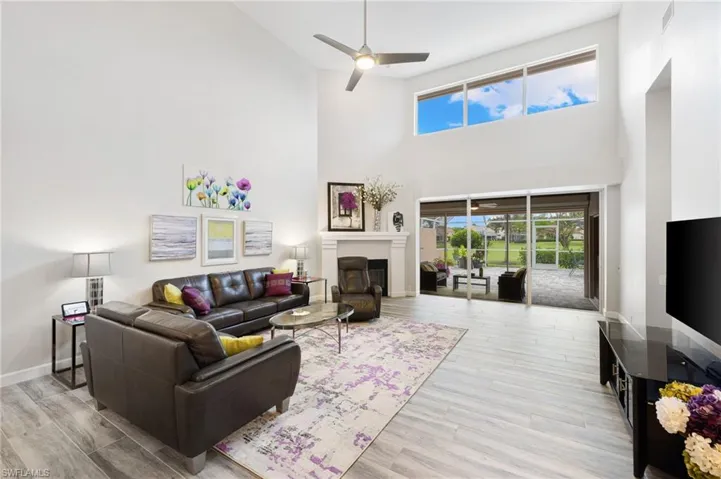 Living room featuring light wood-type flooring, a towering ceiling, and ceiling fan