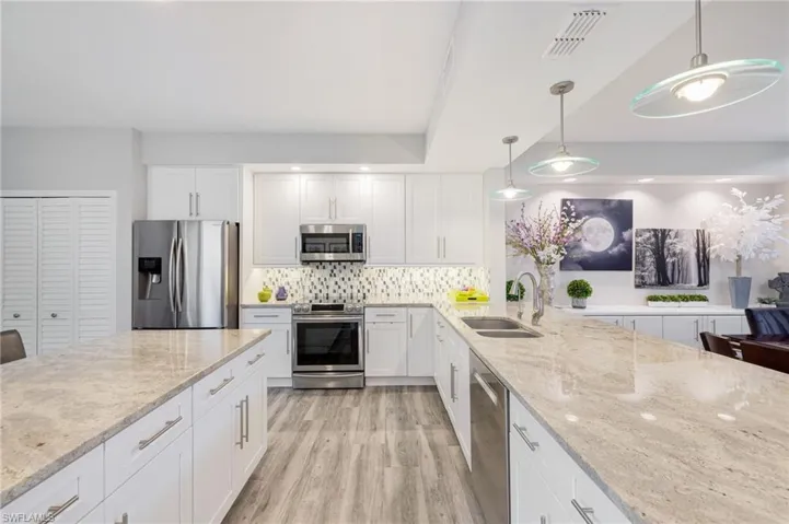 Kitchen featuring light hardwood / wood-style flooring, appliances with stainless steel finishes, decorative light fixtures, sink, and tasteful backsplash