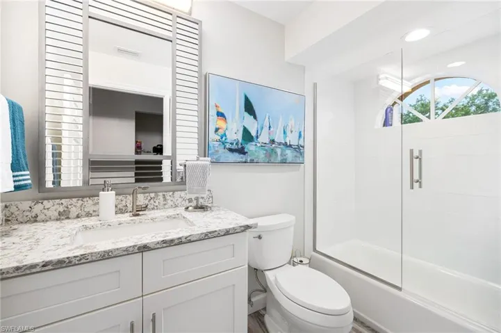 Full bathroom featuring vanity with extensive cabinet space, bath / shower combo with glass door, and toilet