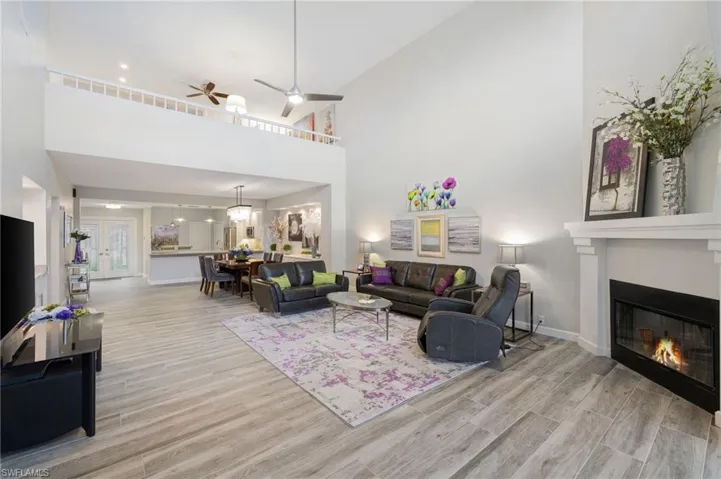 Living room with ceiling fan with notable chandelier, light hardwood / wood-style floors, and a towering ceiling