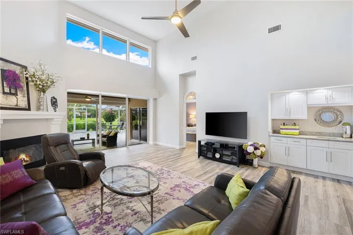 Living room with high vaulted ceiling, ceiling fan, sink, and light hardwood / wood-style floors