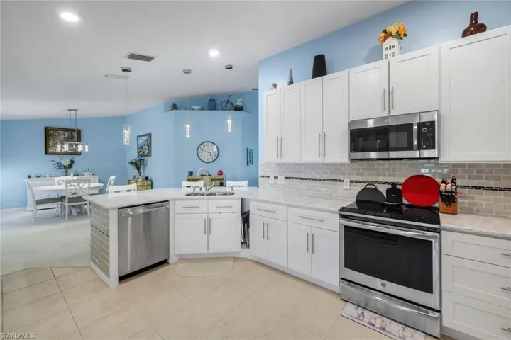 Kitchen featuring white cabinetry, stainless steel appliances, light-toned countertops, and a subway tile backsplash