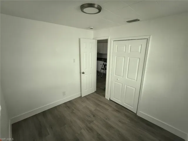 Unfurnished bedroom with dark wood-style floors and a closet