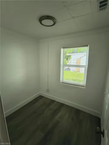 Spare room with dark wood-style floors and baseboards