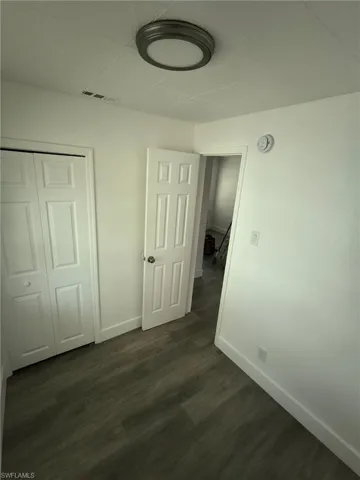 Unfurnished bedroom with dark wood-style floors and a closet