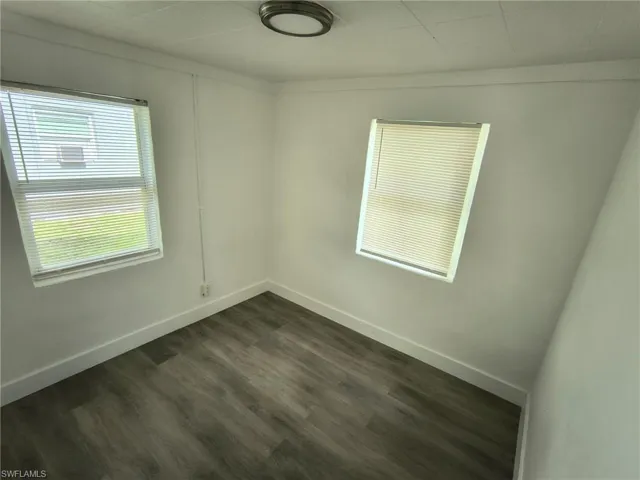 Unfurnished room with dark wood-type flooring and healthy amount of natural light