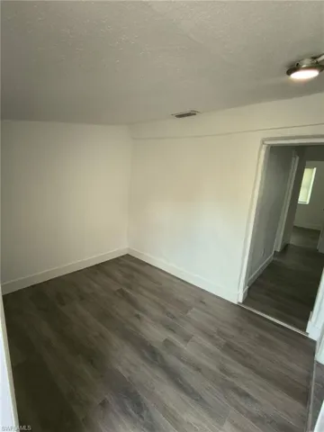Empty room featuring a textured ceiling and dark wood finished floors