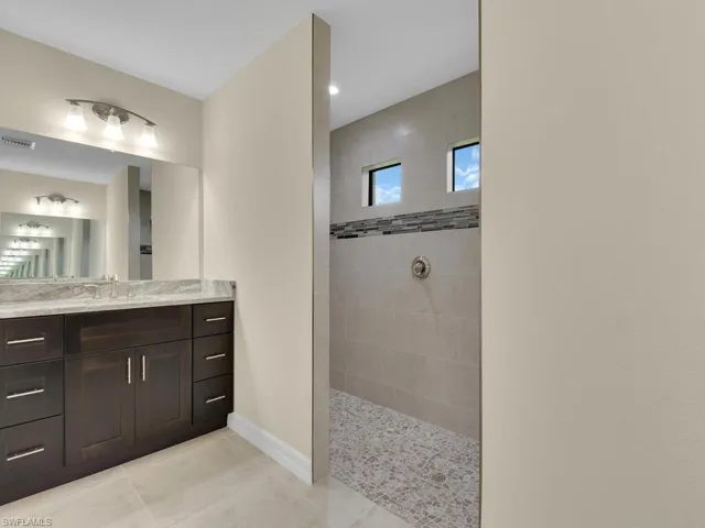 Bathroom featuring tile patterned flooring, a tile shower, and vanity