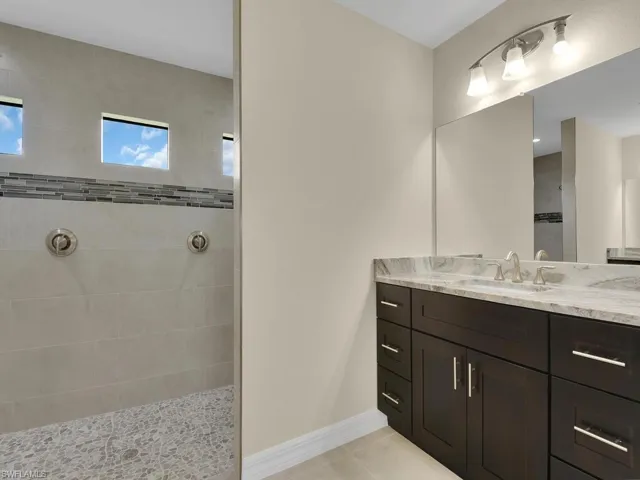 Bathroom with tile patterned floors, vanity, and tiled shower