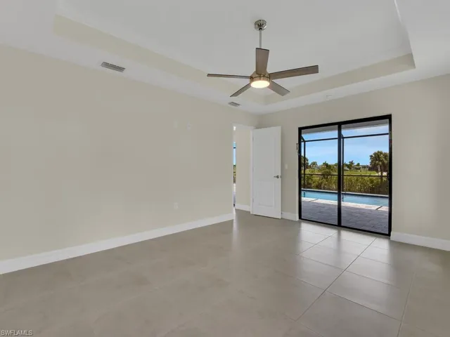 Unfurnished room with a tray ceiling, ceiling fan, and light tile patterned flooring