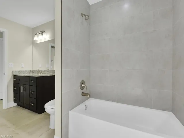 Full bathroom with tile patterned floors, vanity, toilet, and tiled shower / bath