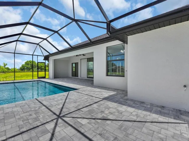 View of swimming pool featuring ceiling fan, a patio area, and glass enclosure