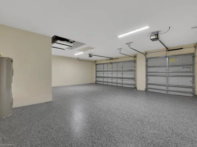 Garage featuring electric water heater and a garage door opener