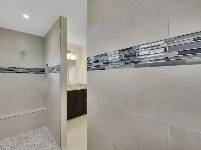 Bathroom featuring tiled shower and vanity
