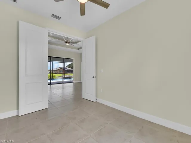 Empty room with beamed ceiling, ceiling fan, and light tile patterned flooring