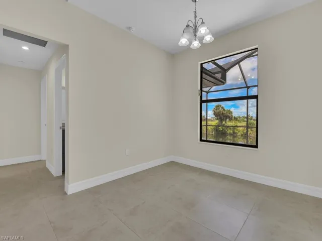 Tiled empty room featuring a chandelier