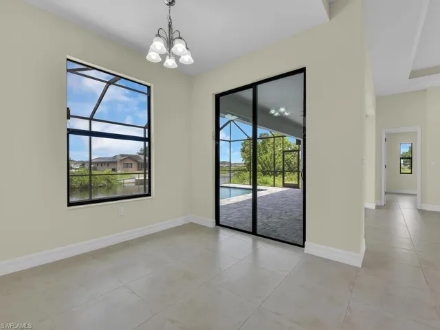 Empty room with light tile patterned floors, a wealth of natural light, and a notable chandelier