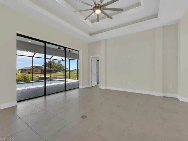 Tiled empty room with a raised ceiling, ceiling fan, and crown molding