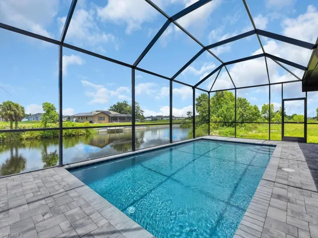 View of swimming pool with a lanai, a water view, and a patio