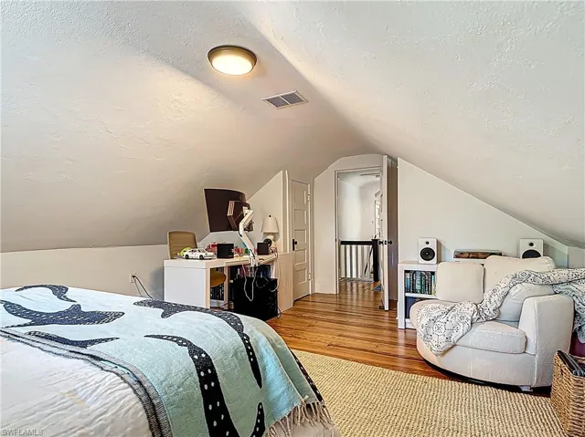 Bedroom featuring vaulted ceiling, visible vents, wood finished floors, and a textured ceiling